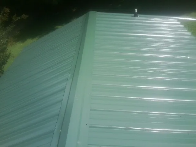 New green metal panels meeting at the ridge of a roof — Flat Roof Repair work by our crew in Limerick