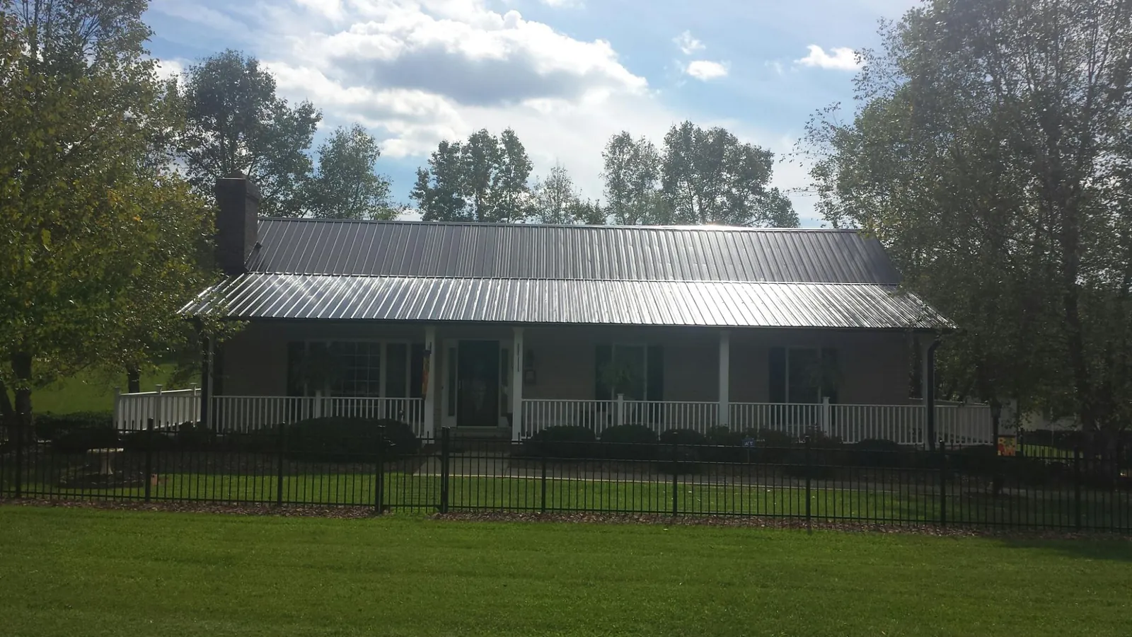 Gray metal roof on a brick ranch with a full width front porch — Gutter Guard Installation work by our crew in Limerick