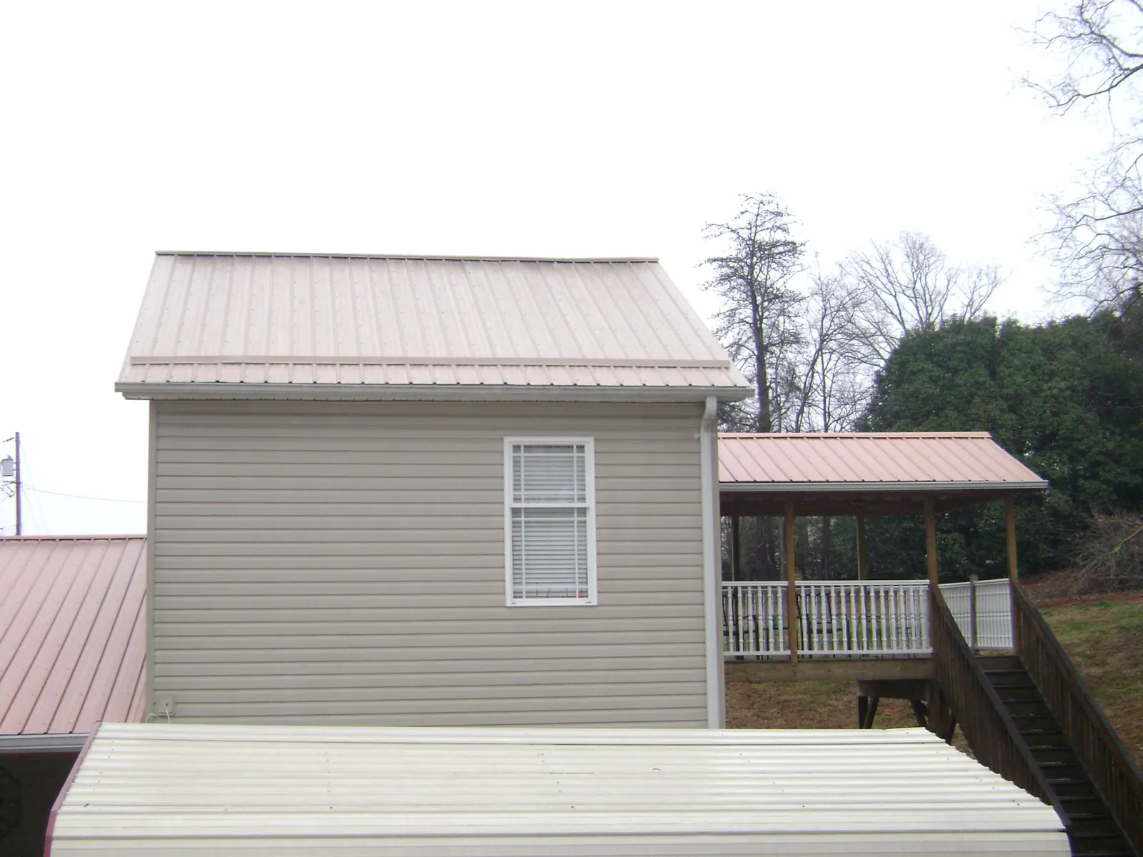 Tan metal roofs on a two story addition and attached porch, from a Roof Replacement job in Limerick