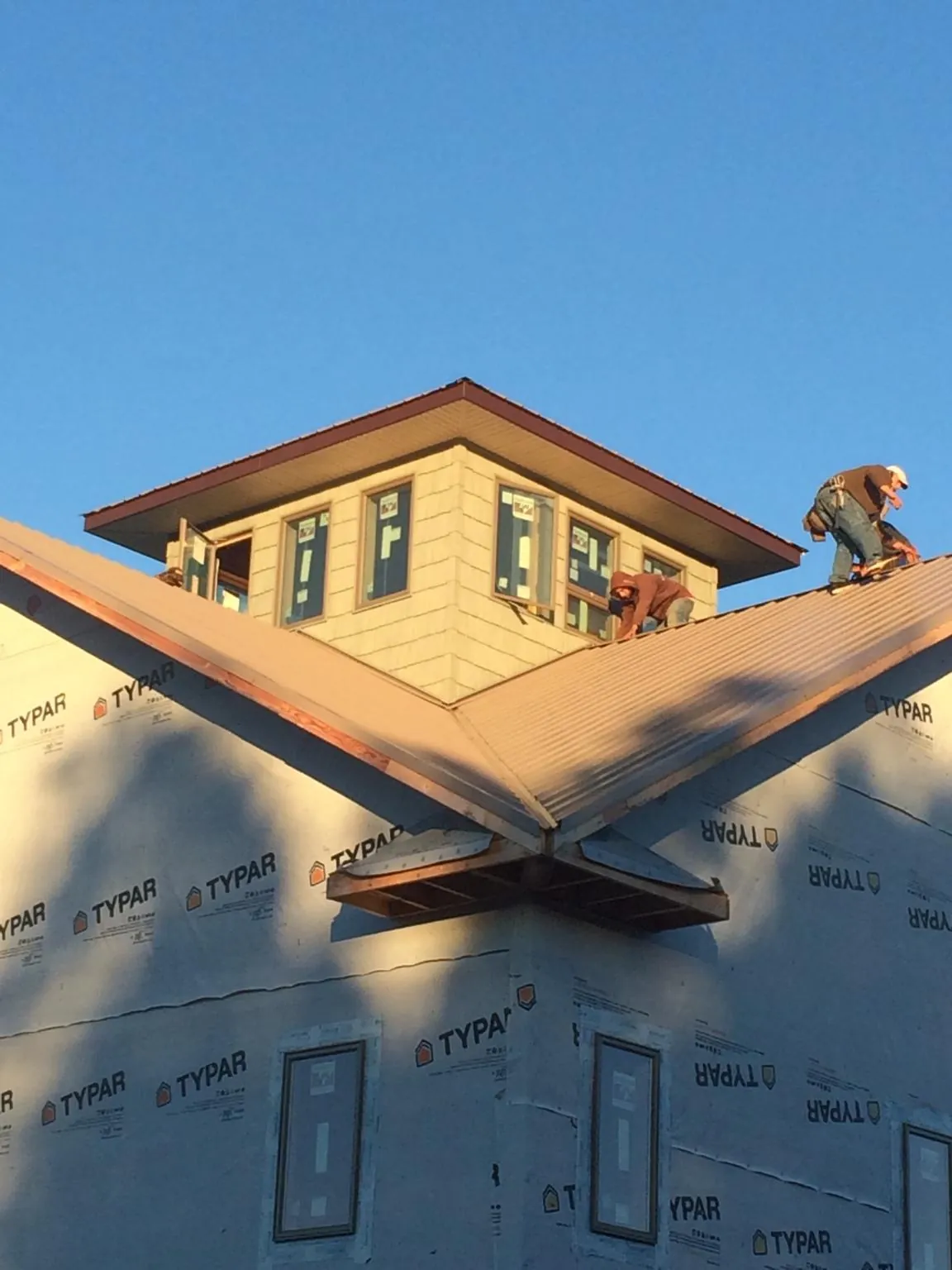 Roofers working around a rooftop cupola on a new metal roof at sunset — Roof Waterproofing in Limerick by Roofing Brothers